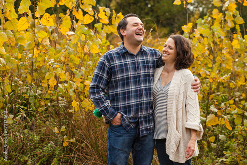 a laughing couple stand in embrace in a golden prairie