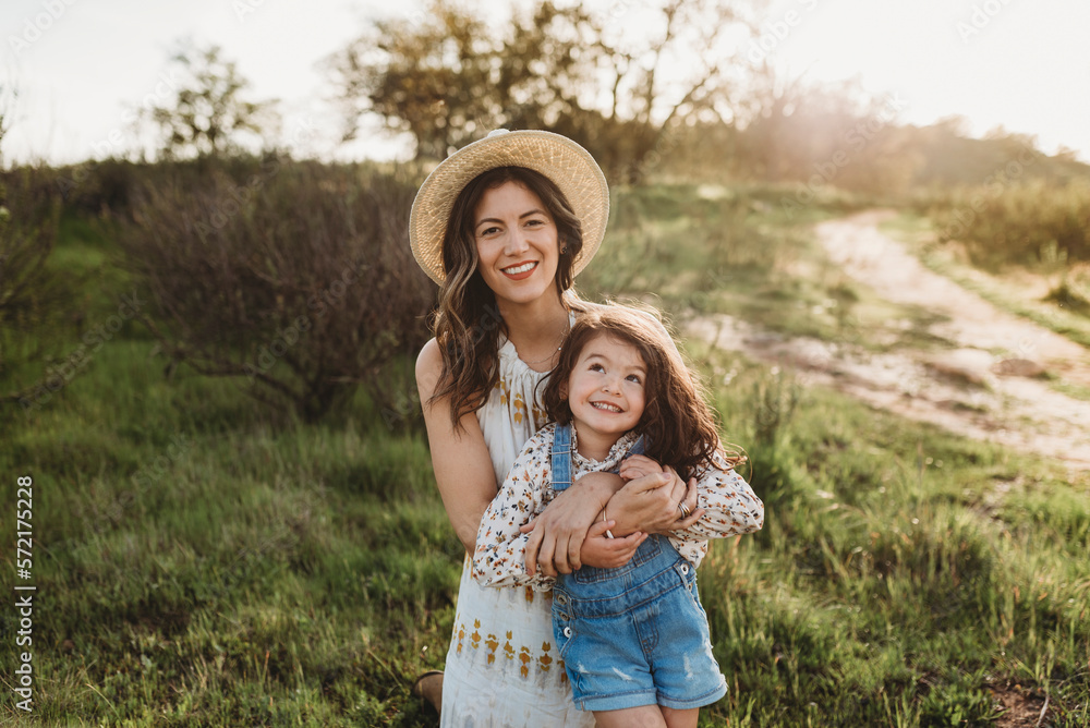 Portrait of happy young mother and daughter smiling in backlit meadow Portrait of happy young mother and daughter smiling in backlit meadow