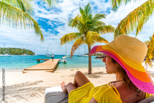 Woman relaxing on beach bed on white sand beach, Caribbean