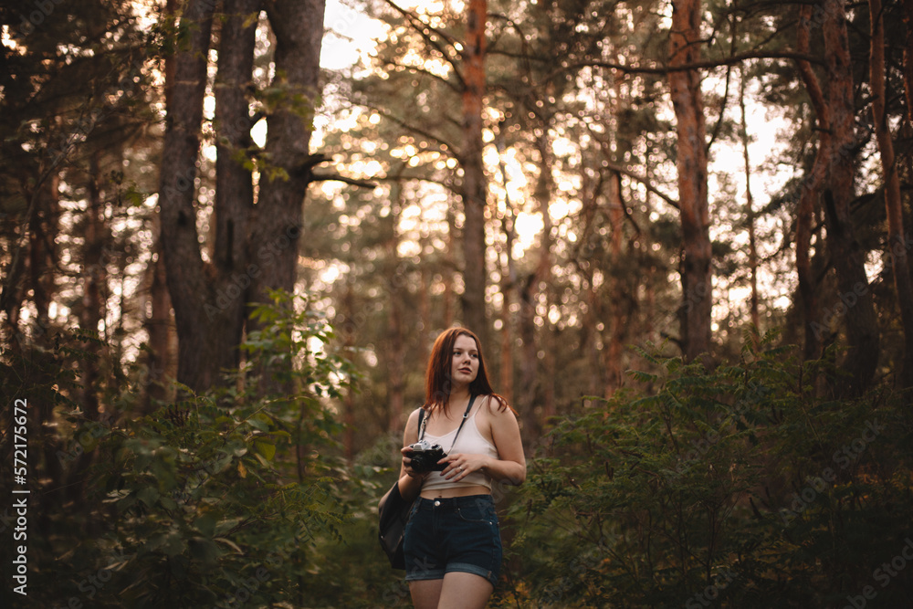 Young woman holding camera while walking in forest Young woman holding camera while walking in forest