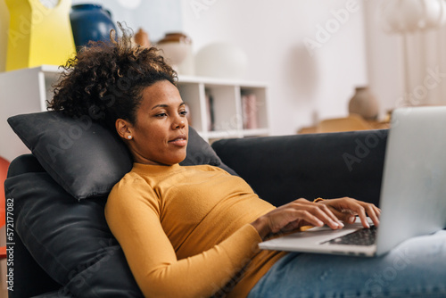Photography Middle aged woman lays on the sofa and works from home