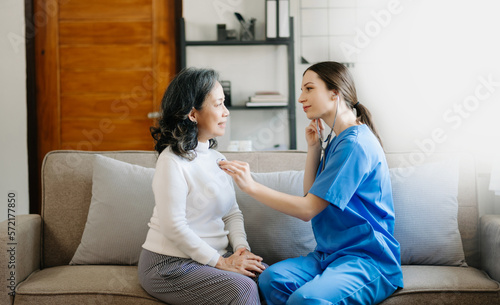 Senior woman being examined by a doctor in background.