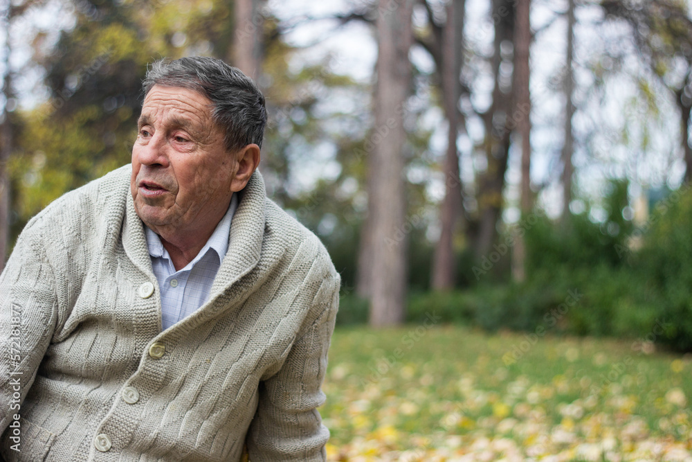 Senior man sitting on a grass alone. Around of a nature