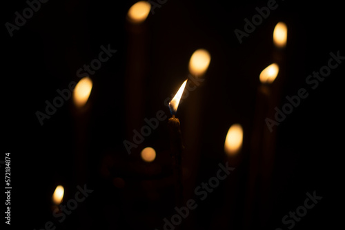 Candles burn in dark. Candle lights. Flames on black background.