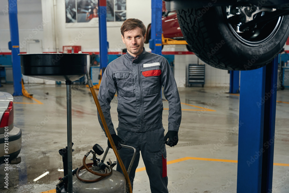 Mechanic standing near engine oil remover in the workshop