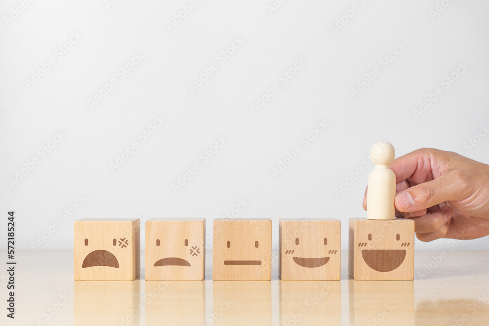 Customer holding wood person model choose smile face emoticon. Concept for Service rating, feedback and satisfaction Customer holding wood person model choose smile face emoticon. Concept for Service rating, feedback and satisfaction