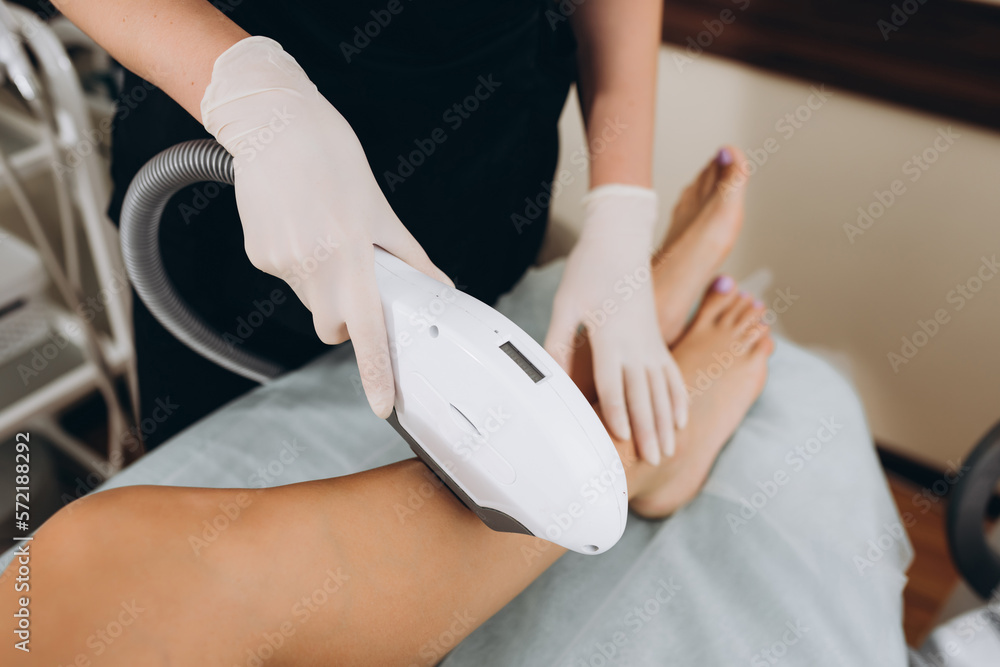 Beautician removes hair on beautiful female legs using a laser. hair removal on the legs, laser procedure at clinic
