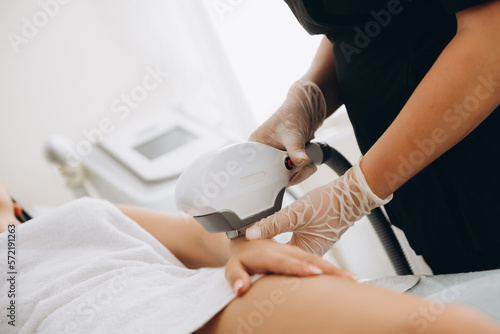 Body Care. Legs Laser Hair Removal. Beautician Removing Hair Of Young Woman's Leg. Laser Epilation Treatment In Cosmetic Beauty Clinic. Hairless Smooth And Soft Skin. Health And Beauty Concept.