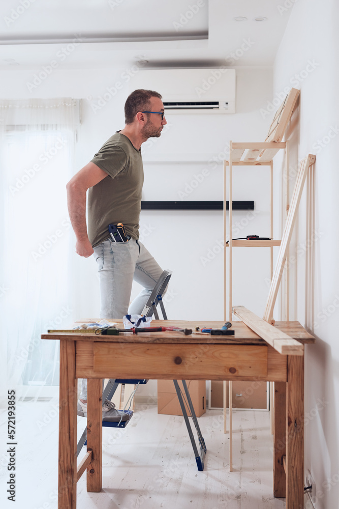 Man assembling new wooden shelf and furniture in the apartment. Man assembling new wooden shelf and furniture in the apartment.