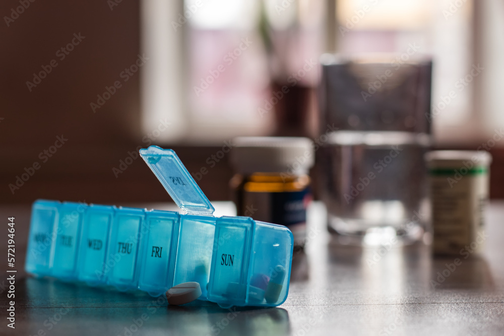 Pill organizer with variety of pills and supplement. Weekly Pill Organizer on the table.