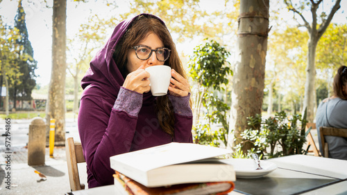 Wallpaper Mural Woman girl, drinking coffee in a park with book and notebook holding mug with two hands with glasses and a purple hoodie Torontodigital.ca