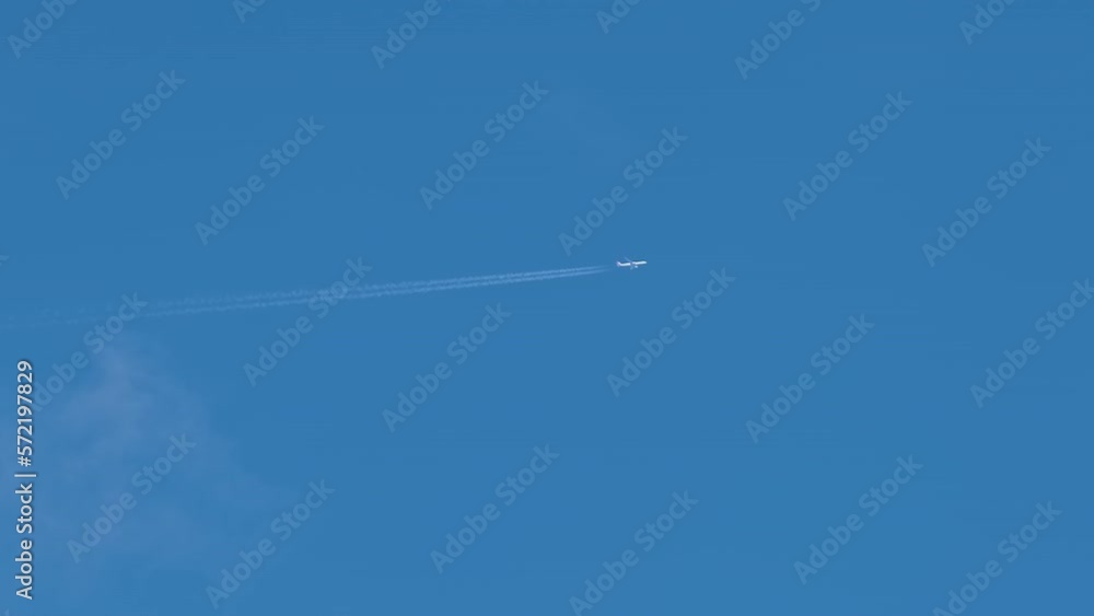 Distant passenger jet plane flying on high altitude on blue sky with white clouds leaving smoke trace of contrail behind. Air traveling concept Distant passenger jet plane flying on high altitude on blue sky with white clouds leaving smoke trace of contrail behind. Air traveling concept