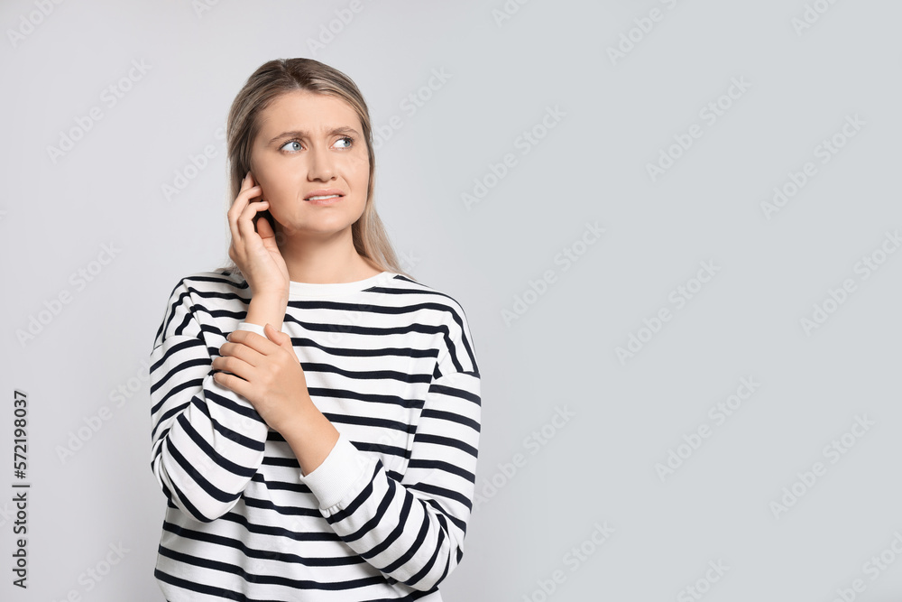 Young woman suffering from ear pain on light grey background. Space for text Young woman suffering from ear pain on light grey background. Space for text