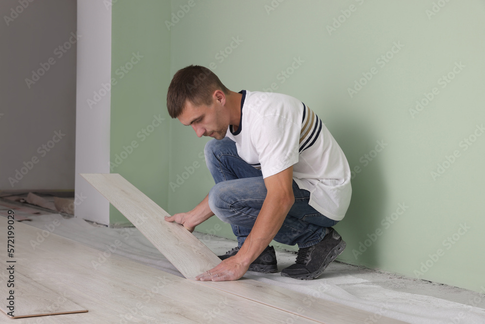 Man installing new laminate flooring in room Man installing new laminate flooring in room
