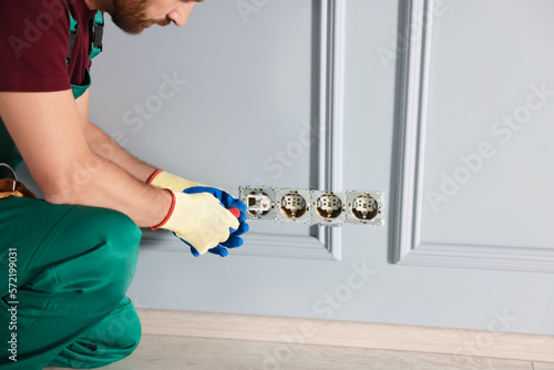 Electrician with screwdriver repairing power sockets indoors, closeup