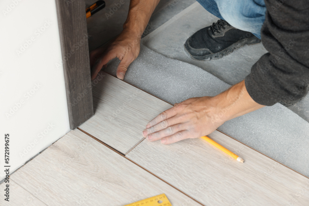 Worker installing new laminate flooring in room, closeup Worker installing new laminate flooring in room, closeup