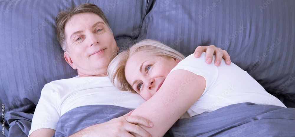 Mature heterosexual beautiful couple lying on bed in bedroom