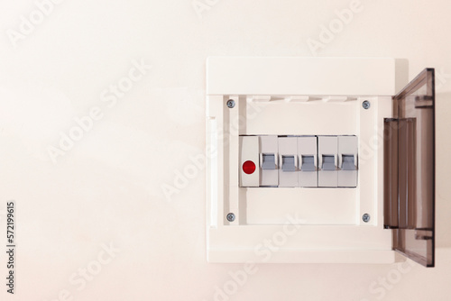 Open fuse box on beige wall. Space for text