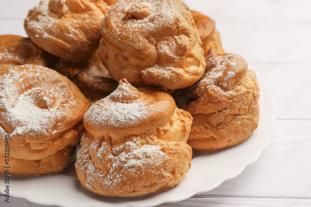 Delicious profiteroles with powdered sugar on white table, closeup Delicious profiteroles with powdered sugar on white table, closeup