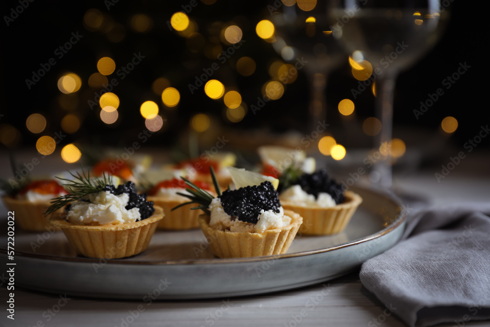 Φωτογραφία Delicious tartlets with red and black caviar served on white wooden table against blurred festive lights, closeup