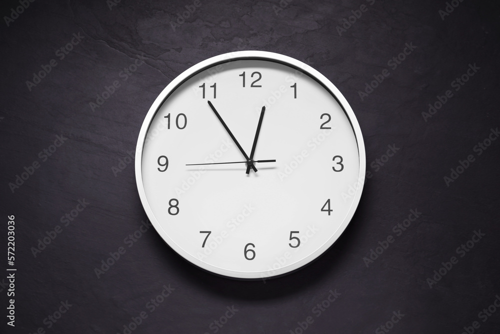 Stylish round clock on black table, top view. Interior element