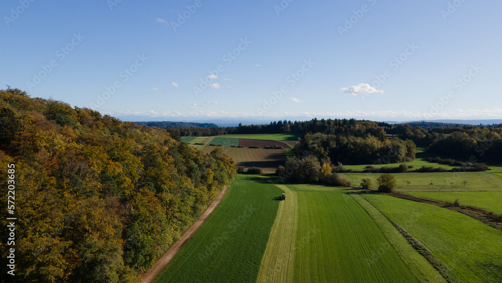 Drone aerial photography of countryside with field, farmers at work and blue sky of a late summer day