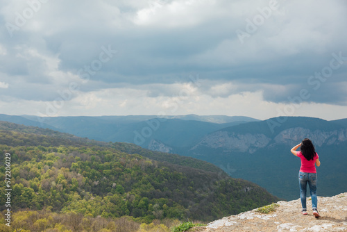 a woman on top of a mountain looks into the distance nature of the sky in the clouds