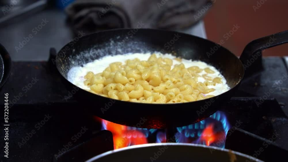 Cooking stovetop macaroni and cheese, professional chef adding al dente