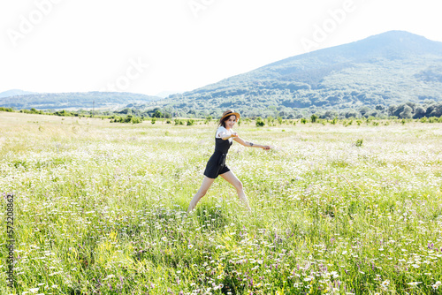 woman running around the field in chamomile flowers green grass