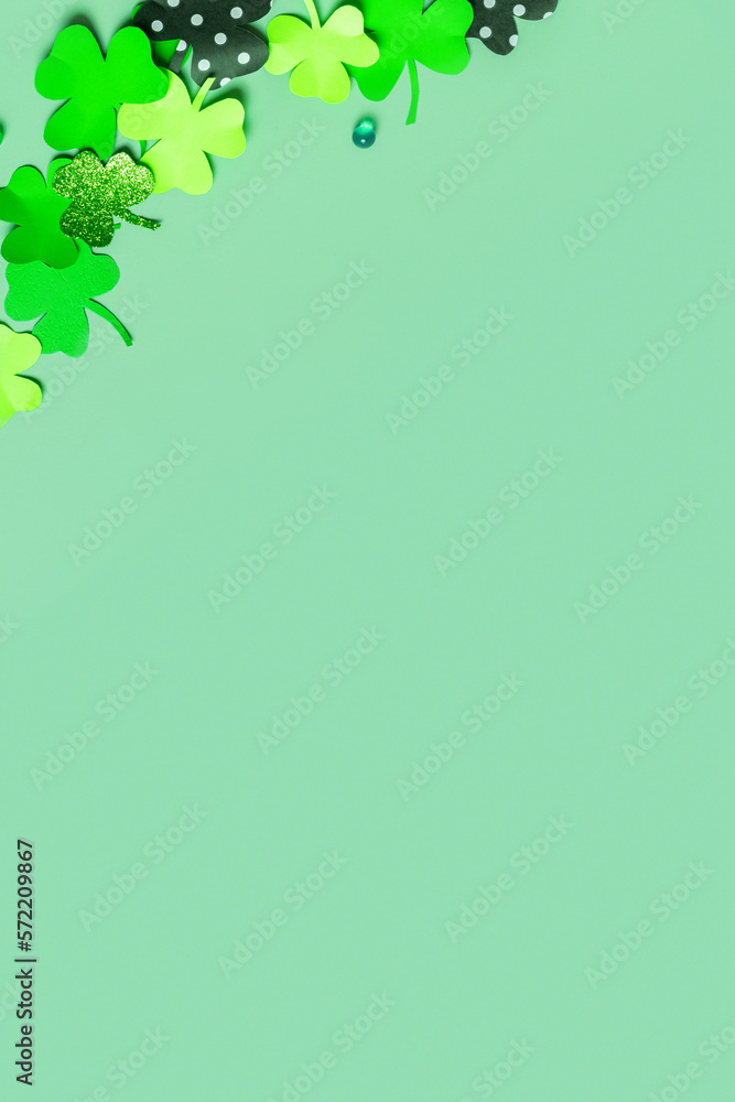 St. Patrick's Day flat lay vertical background. Paper clover leaves on colored background with copy space