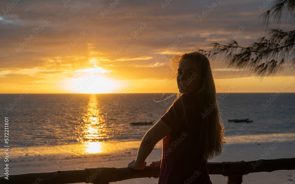Beautiful young blonde girl enjoying the sunrise on a beach in Zanzibar (Africa)
