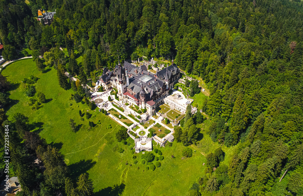 Aerial view of Peles Castle with Bucegi Mountains in background during a beautiful sunny day. Landmarks of Romania.