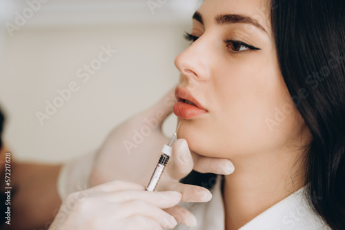 Portrait of young Caucasian woman getting botox cosmetic injection in forehead. Beautiful woman gets botox injection in her face