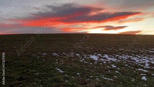 Sunset at the meadow with grass covered with melting snow