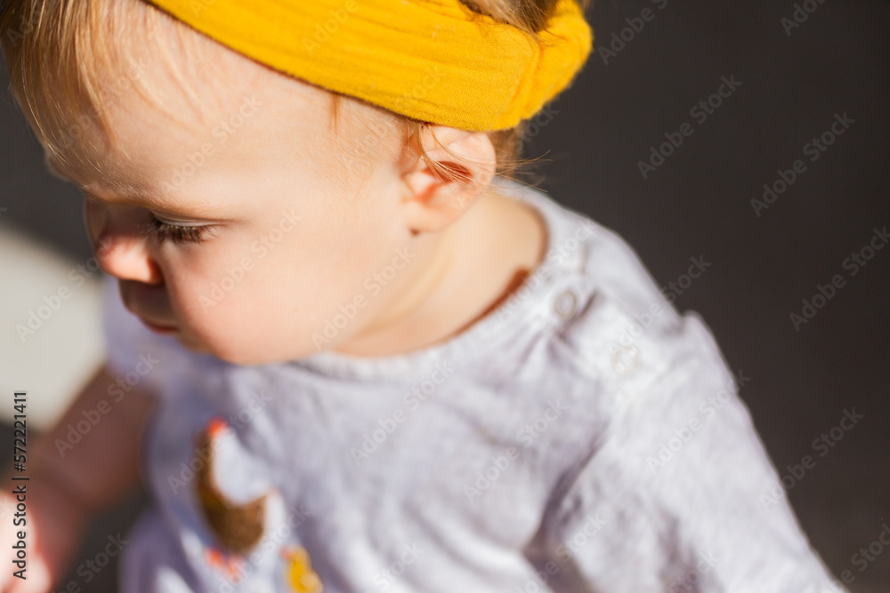 detail of baby face with yellow headband and ear in sunlight outside detail of baby face with yellow headband and ear in sunlight outside