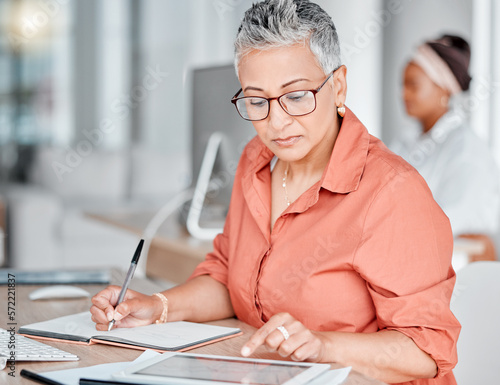 Tablet, book and business woman writing, research or internet browsing in office workplace. Technology, notebook and senior female employee with touchscreen for taking notes and planning strategy.