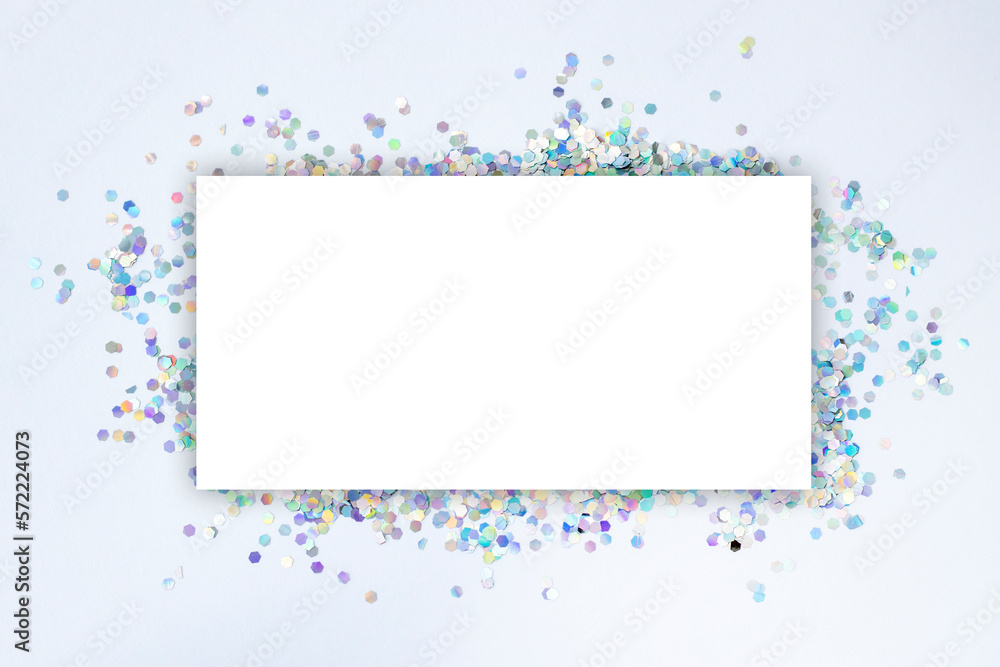 White blank mock-up sheet with a background of silver holographic confetti scattered on the surface.