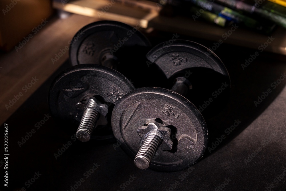 A portrait of two dumbbell weights lying on a small mat ready to be used for some healthy exercises for strength, stamina or to recover from an injury. Great for a new years resolution. A portrait of two dumbbell weights lying on a small mat ready to be used for some healthy exercises for strength, stamina or to recover from an injury. Great for a new years resolution.