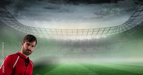 Composition of portrait of sportsman over pitch in misty sports stadium with cloudy sky