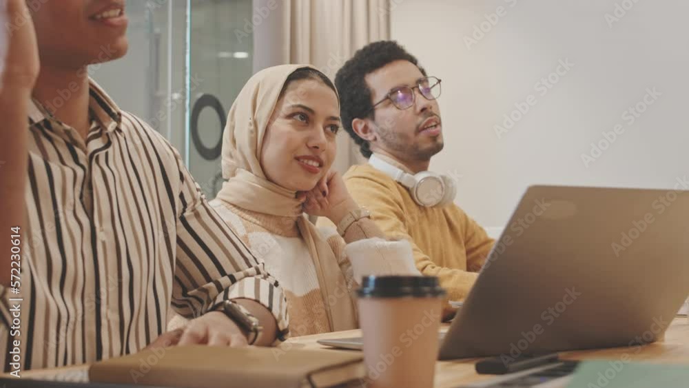 Waist up shot of three multiethnic young male and female coworkers having brainstorm meeting in modern conference room Waist up shot of three multiethnic young male and female coworkers having brainstorm meeting in modern conference room