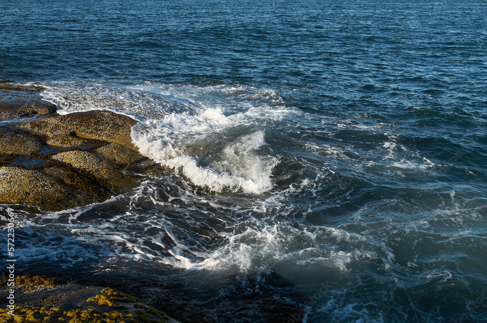 Fototapeta premium Surf on the coastline of the north sea with a mountainous coast in the background