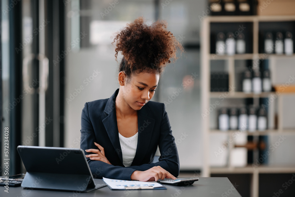 Beautiful Asian woman using laptop and tablet while sitting at her working place. Concentrated at work. Beautiful Asian woman using laptop and tablet while sitting at her working place. Concentrated at work.