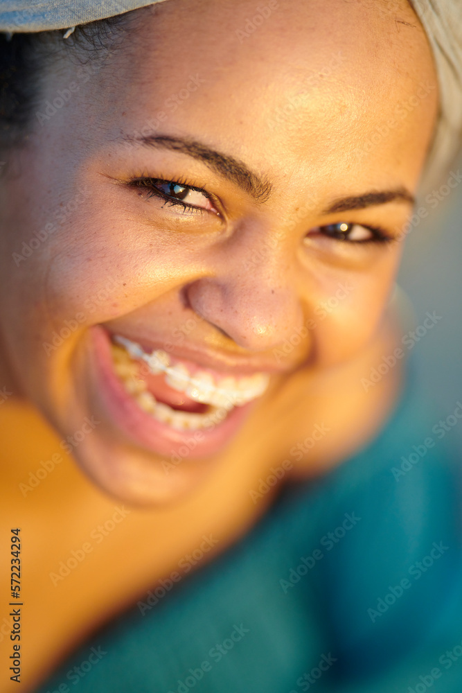 Smiling woman in sunlight.. Close-up of pretty happy woman with braces laughing, looking at camera in bright sunlight casting over her face. Smiling woman in sunlight.. Close-up of pretty happy woman with braces laughing, looking at camera in bright sunlight casting over her face.