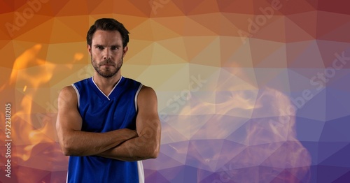 Composition of male basketball player with arms crossed over smoke and flame on blue and red