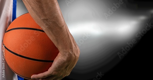Composition of midsection of male basketball player with ball, spotlights and copy space