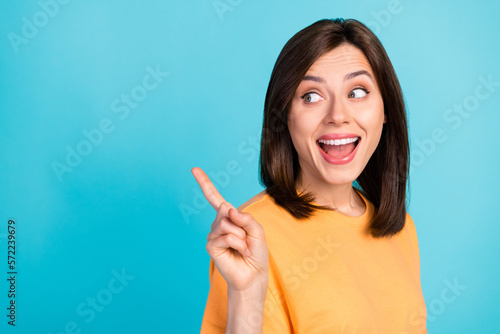 Portrait of positive cheerful woman long hairstyle dressed yellow t-shirt look indicating empty space isolated on blue color background
