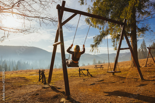 The young girl swinging on wooden old swings in the mountain Sud Tirol forrest, Italy  photo