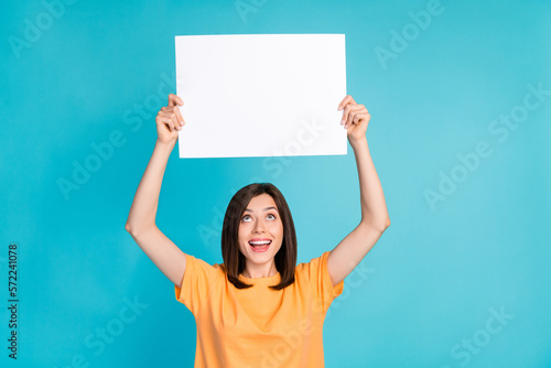 Photo of pretty cute positive lady wear trendy clothes raise arms above head look empty space isolated on blue color background