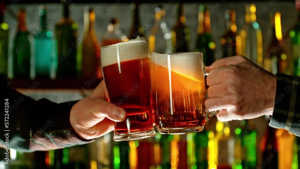 Super slow motion of hitting beer mugs together, cheers concept. Filmed on high speed cinema camera, 1000 fps. Bar with bottles on background. Super slow motion of hitting beer mugs together, cheers concept. Filmed on high speed cinema camera, 1000 fps. Bar with bottles on background.