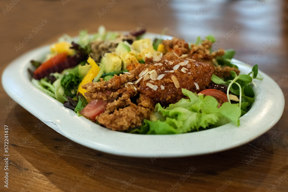 A large vegetable salad with battered fried crab in a white plate on the dining table, eat together to add balance in the body by eating vegetables